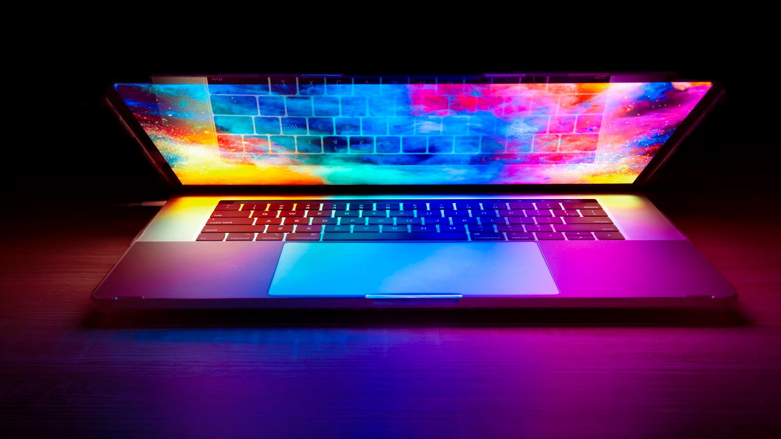 Affiliate commission structures: A laptop with a vibrant colorful screen glowing on a dark wooden desk