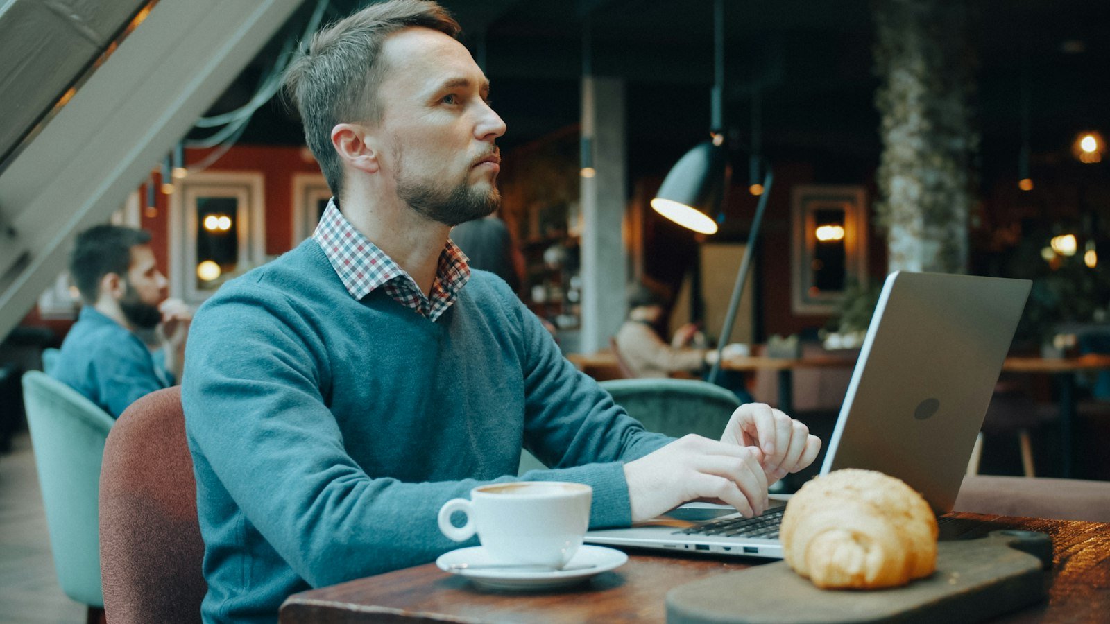 Business opportunity content marketing: A man in a blue sweater typing on a laptop in a cafe