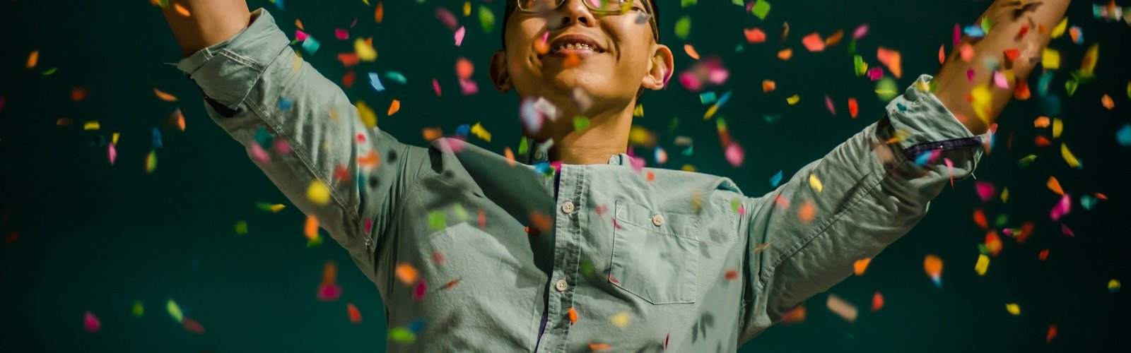 Person celebrating with arms raised as confetti falls