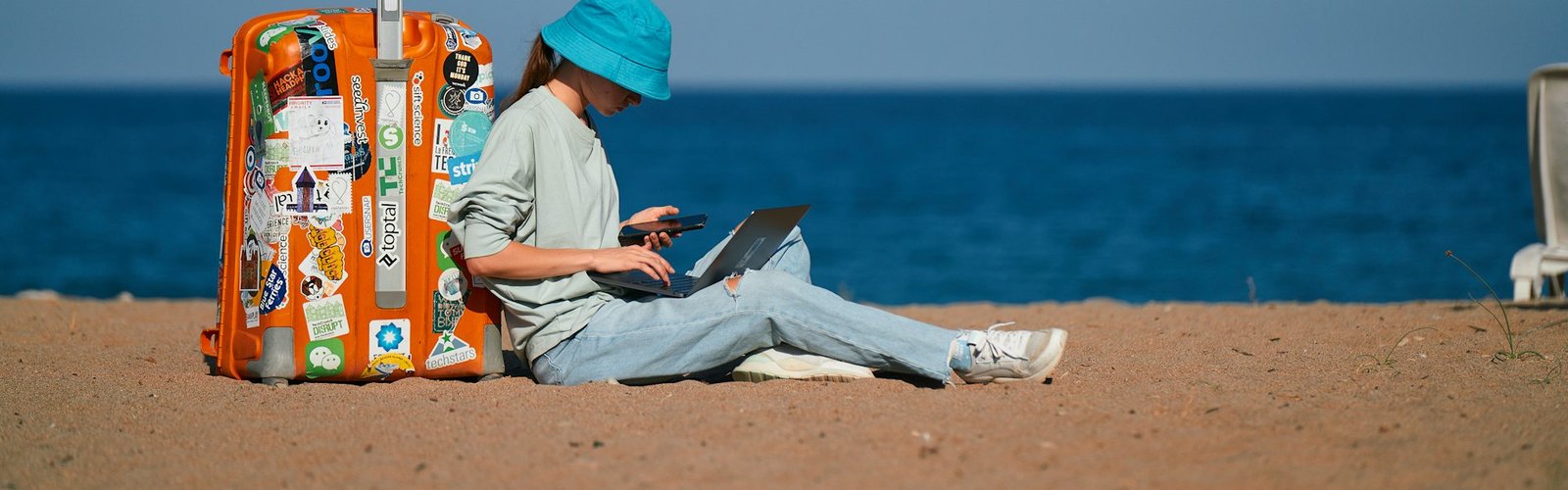 Traveler working on a laptop while sitting on a sandy beach