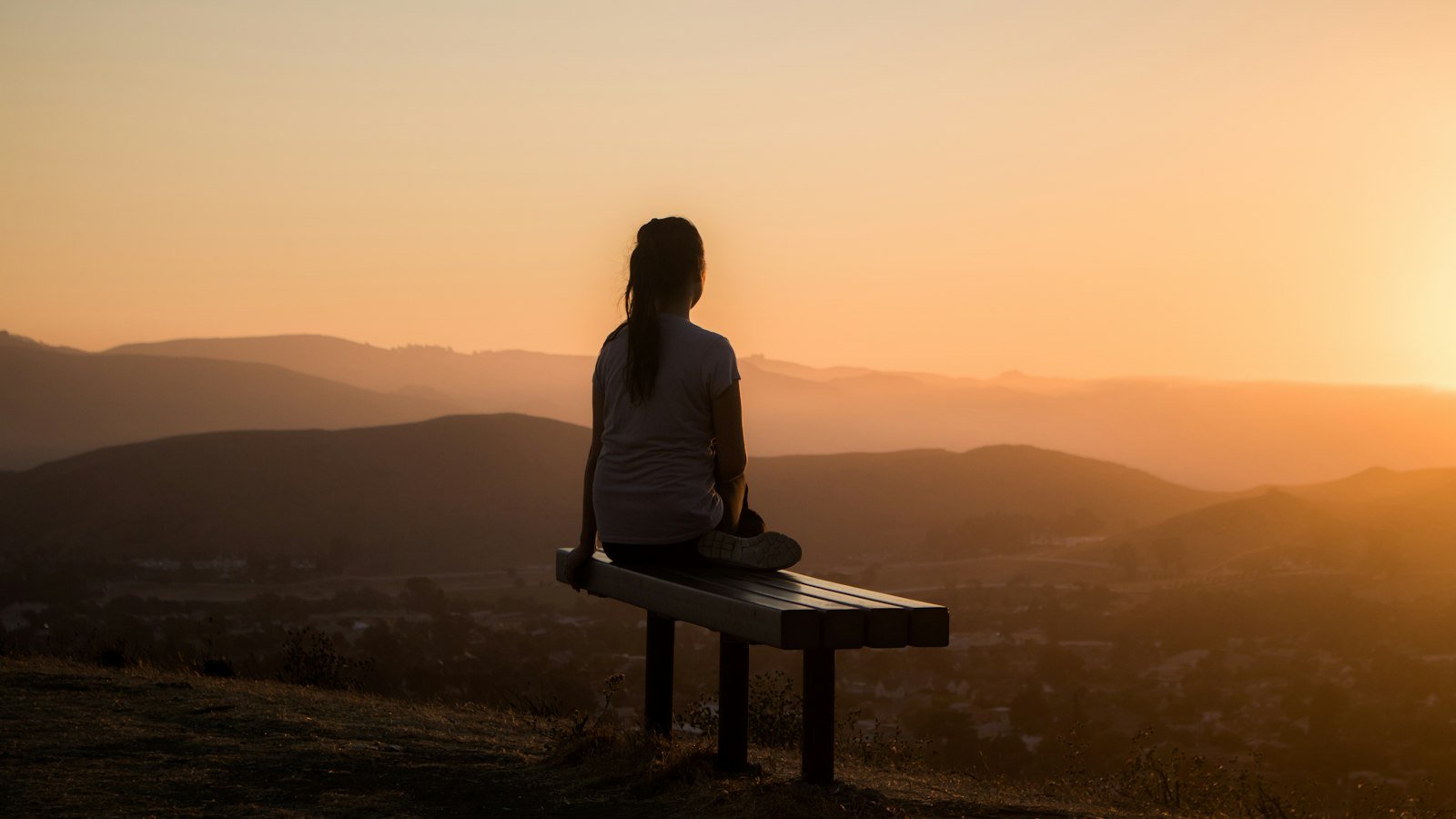 Entrepreneur burnout: woman sitting on bench over viewing mountain