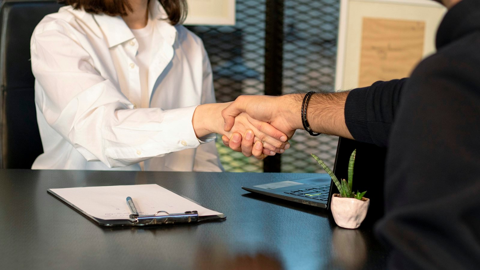Find a business for sale: a man and a woman shaking hands in front of a laptop