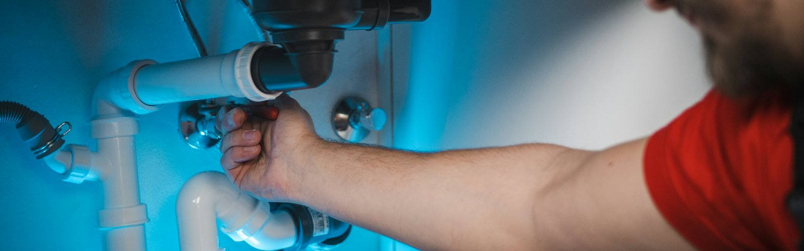 Home services business opportunity: Tradesperson repairing a pipe inside a wall for a home services business