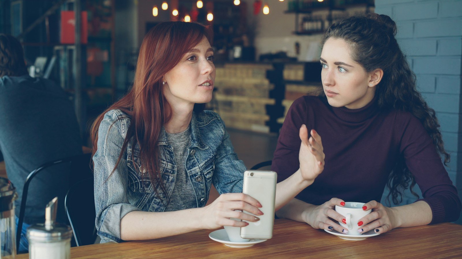 Imposter syndrome for entrepreneurs: Two women converse at a cafe