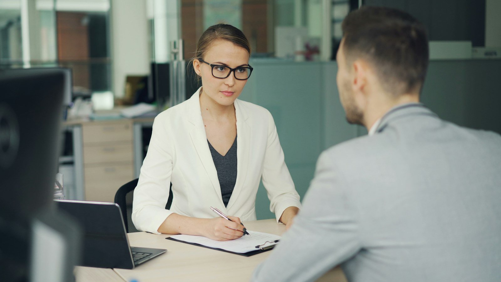 Journaling for entrepreneurs: Woman in glasses interviews man at office desk