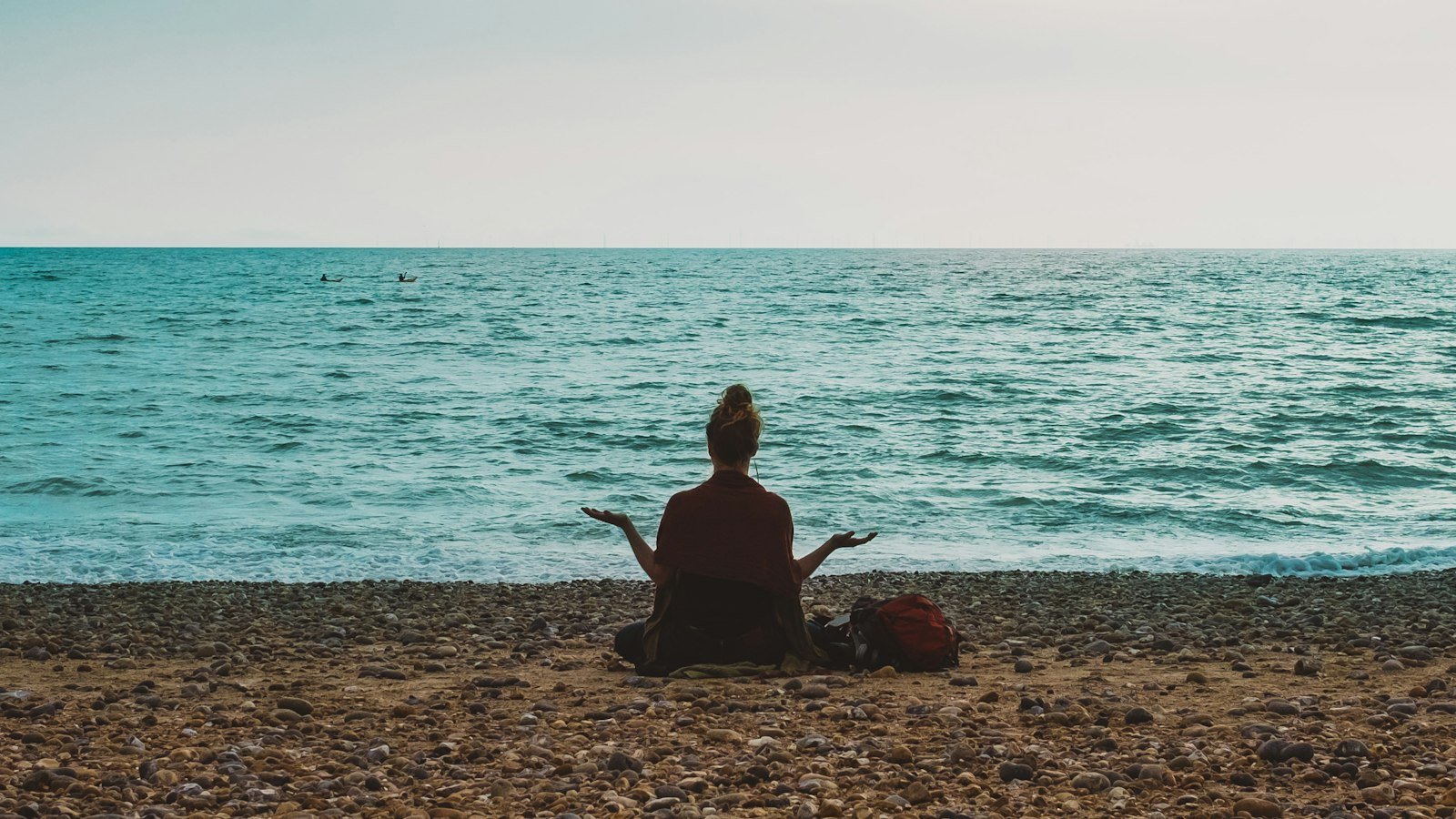 Manage stress as a business owner: person doing yoga on seashore during daytime
