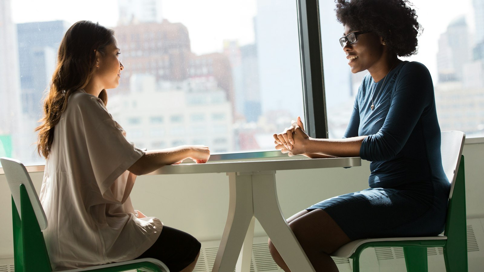 Managing emotions in negotiation: two women sitting beside table and talking