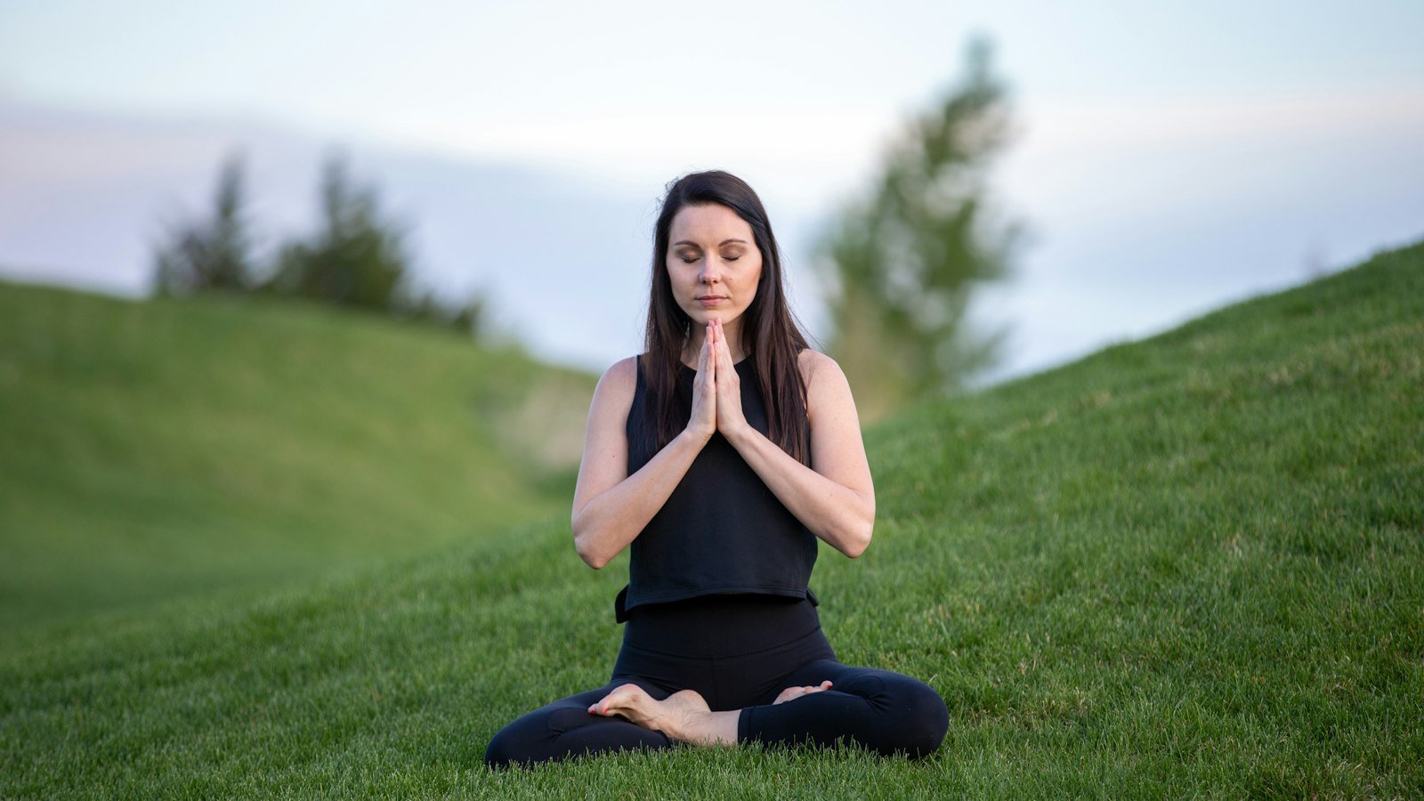 Meditation for entrepreneurs: woman in black tank top and black pants sitting on green grass field during dayt