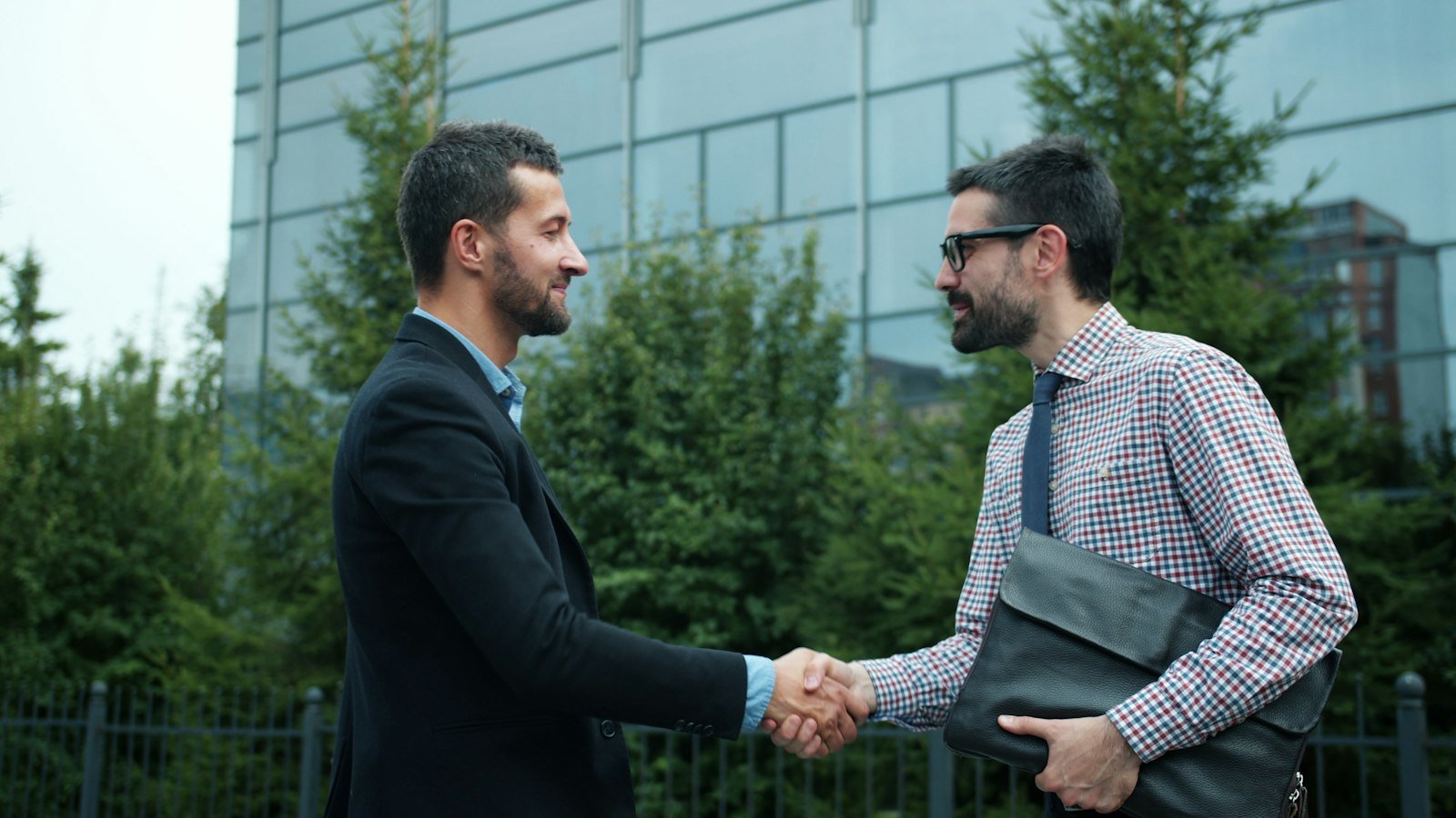Non-compete agreement: Two businessmen shaking hands outside modern building