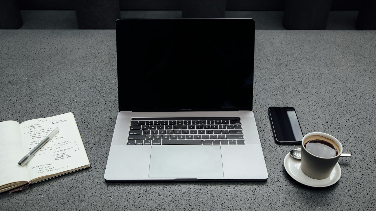 Partner program vs affiliate program: turned-off MacBook Pro between cup of coffee, iPhone, notebook, and pen