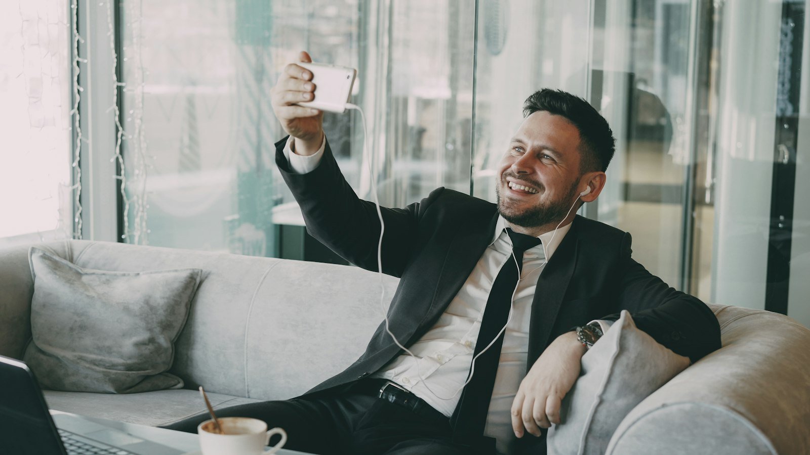 Price a business opportunity: Man in suit taking a selfie on a couch