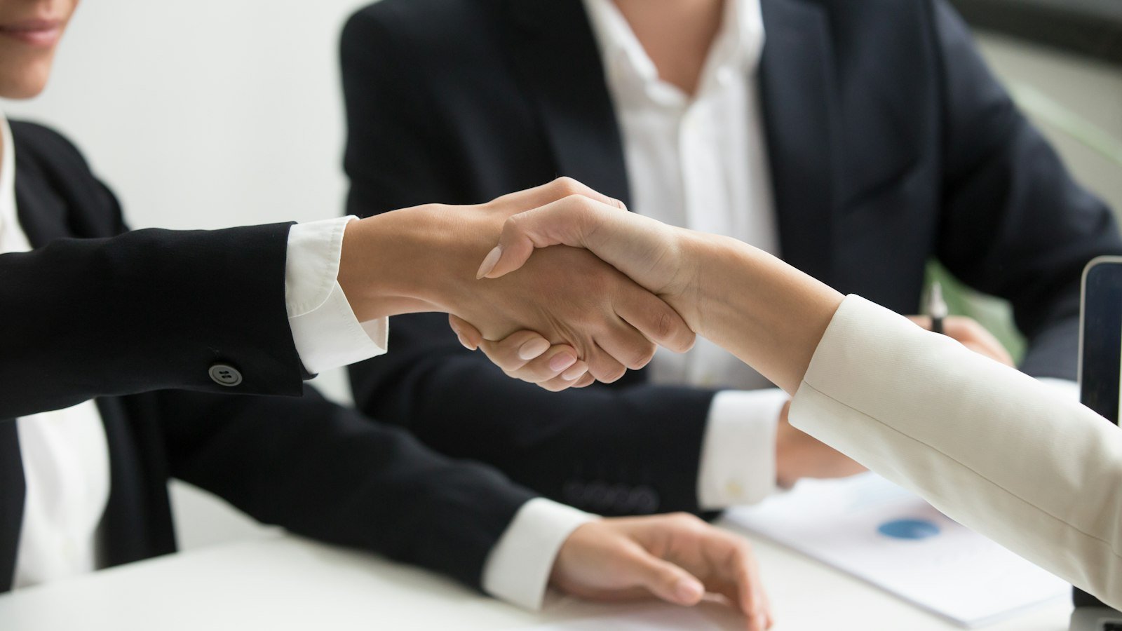 Sell a small business: two people shaking hands in front of a laptop